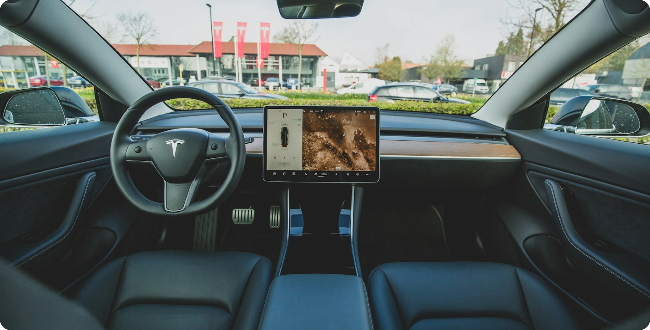 Interiér vozu Tesla s volantem a velkým centrálním dotykovým displejem na palubní desce