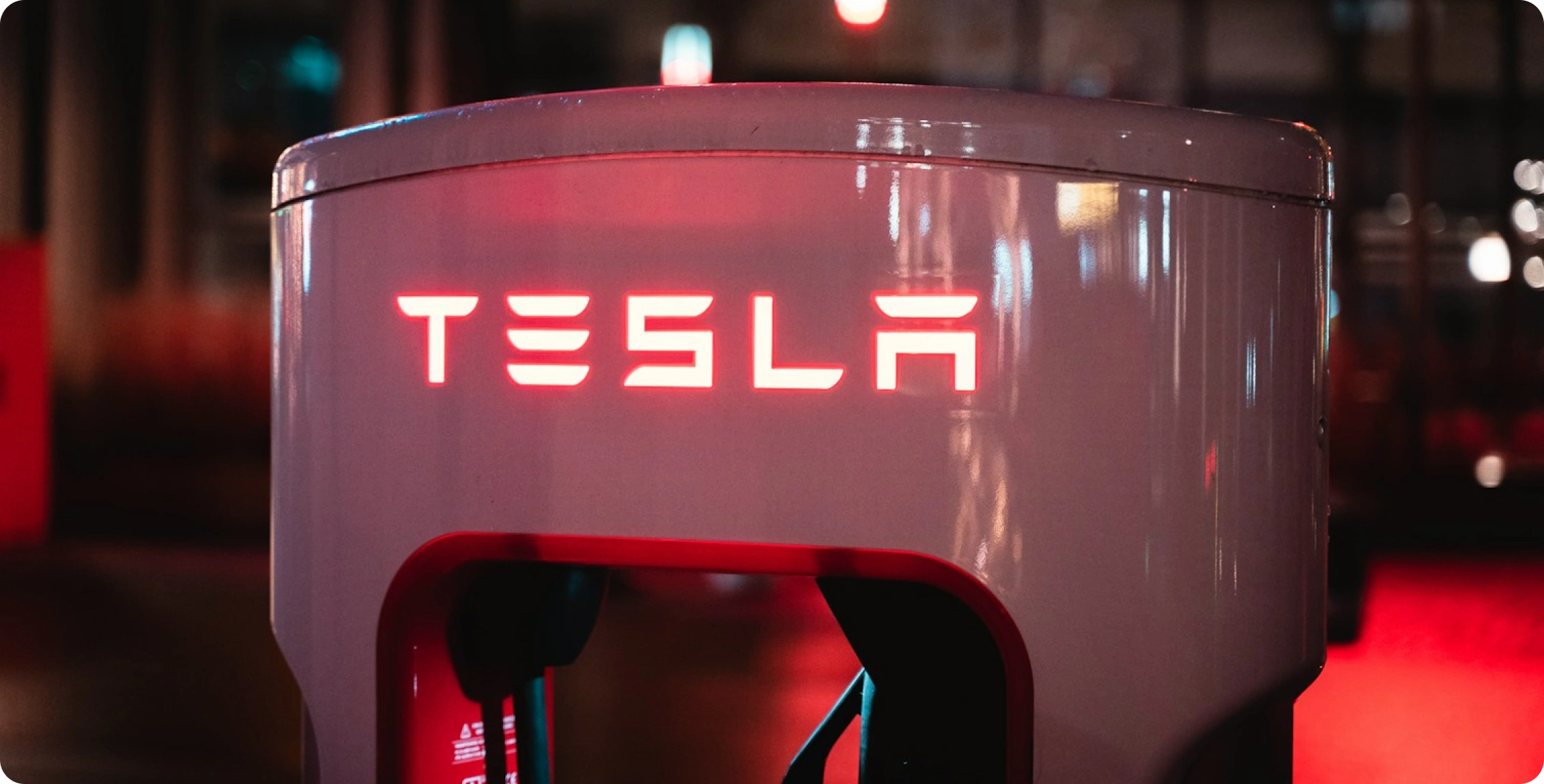 Detail nabíjecí stanice Tesla se svítícím červeným nápisem.