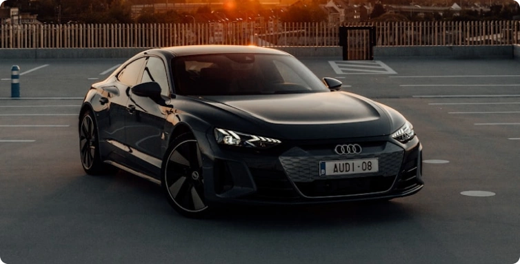 Černé sportovní Audi zaparkované na prázdném parkovišti při západu slunce