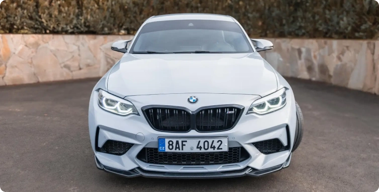 Bílé BMW M2, čelní pohled na sportovní vůz zaparkovaný na příjezdové cestě
